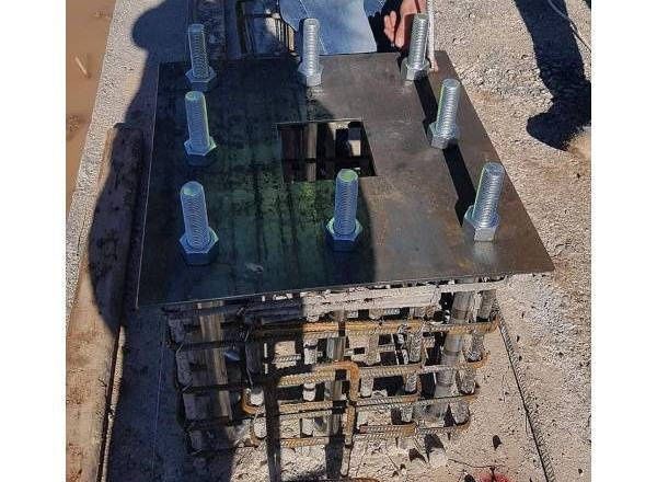 Steel anchor plate with multiple bolts and exposed reinforcement beneath