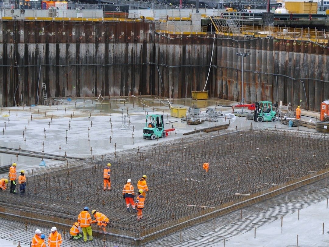 Workers install dense reinforcing steel in a large concrete foundation pit