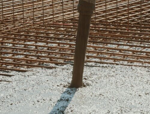 Rust-colored rebar grid and a vertical post embedded in concrete