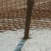 Rust-colored rebar grid and a vertical post embedded in concrete
