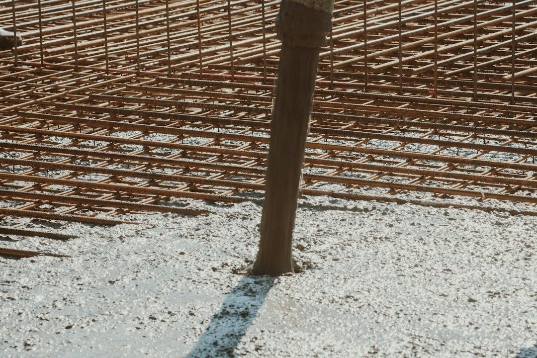 Rust-colored rebar grid and a vertical post embedded in concrete